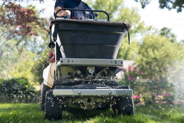 A PRO-TURF Services lawn care professional applies fertilizer with an Ex Mark applicator.