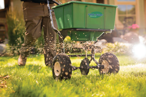 A PRO-TURF Services lawn care professional fertilizes a residential front yard.