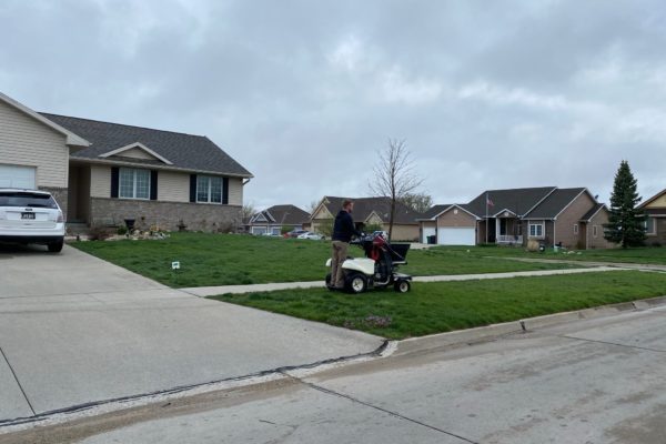 A PRO-TURF Services lawn care professional applies a first application of fertilizer to a residential front yard.
