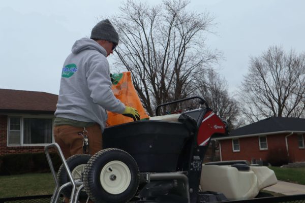 A PRO-TURF Services lawn care professional prepares to fertilize a lawn in a residential neighborhood.