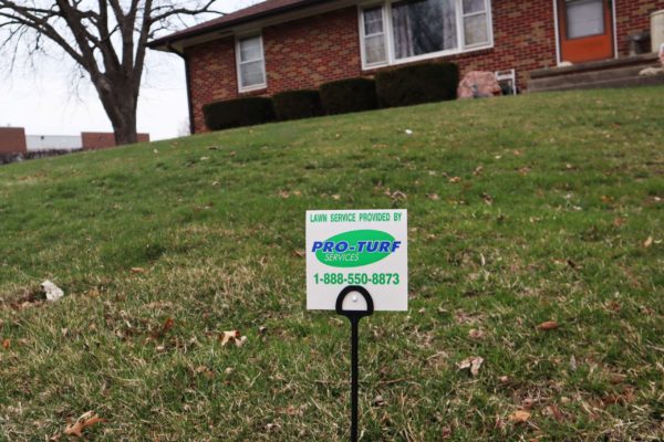 A "Lawn Service Provided by PRO-TURF Services" posted in a cleanly cut lawn.