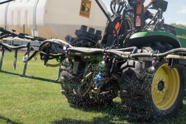 A PRO-TURF Services lawn care professional sprays for weeds on a sports field.